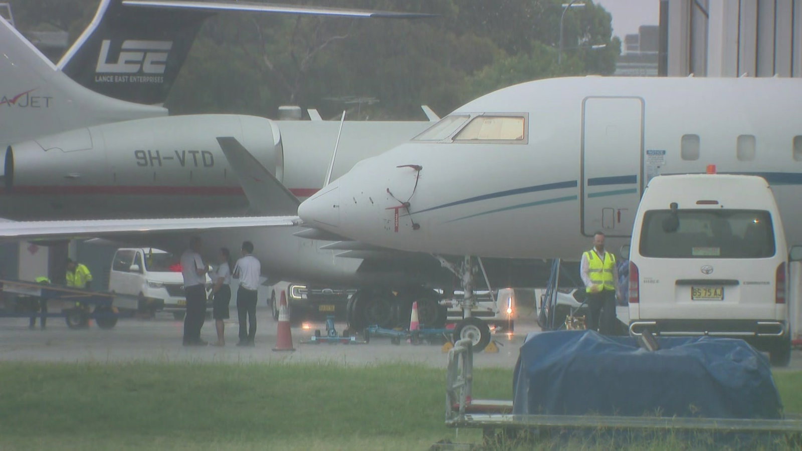 Two jet planes on tarmac with airport staff on the ground