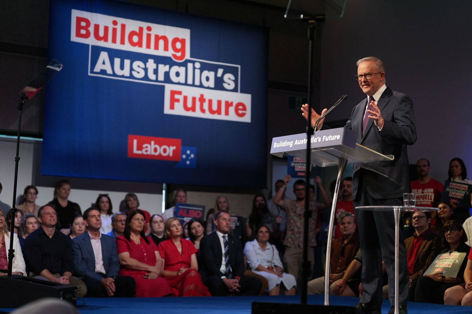 Albanese gestures with two hands as he speaks at a podium