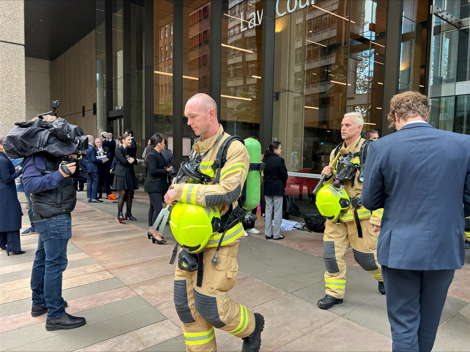 Firemen in bright suits leave court, people milling around