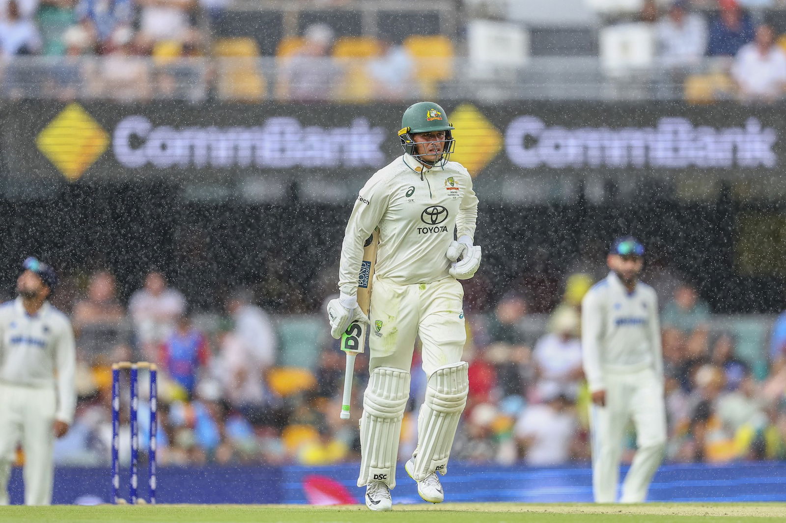 Australia batter Usman Khawaja runs off the field in the rain.