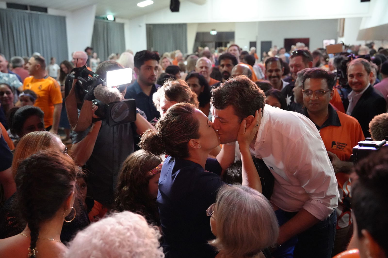 a woman and man kiss in front of crowd