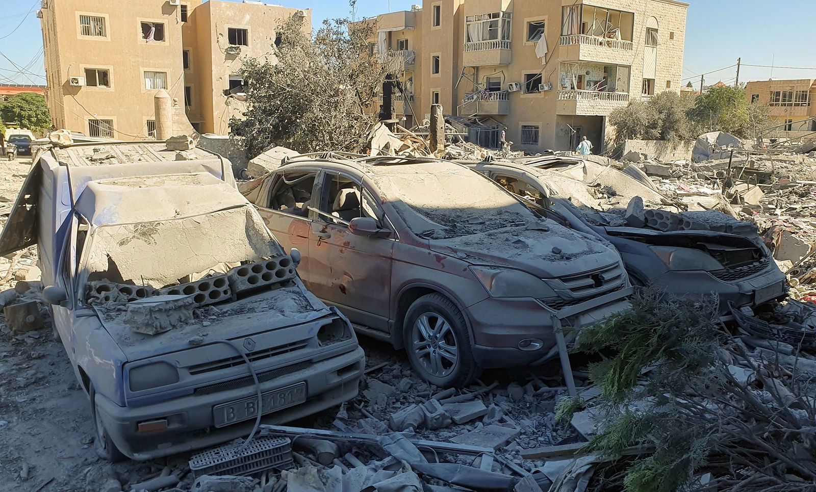 Three cars beside each other covered in rubble.