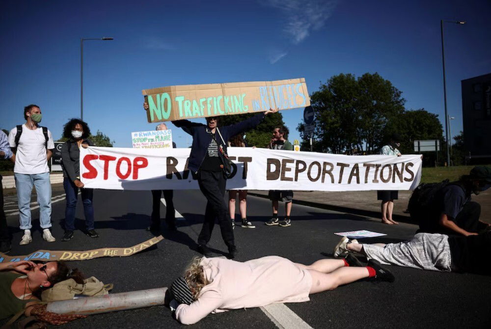 A group of people protesting, including some lying on a road.