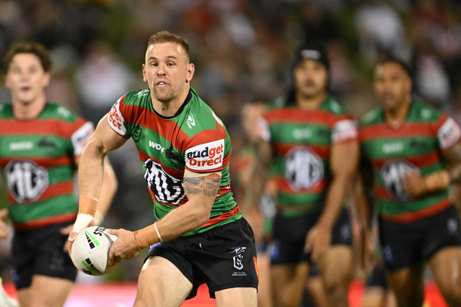 NRL palyer running with the ball in two hands, looking to pass the ball