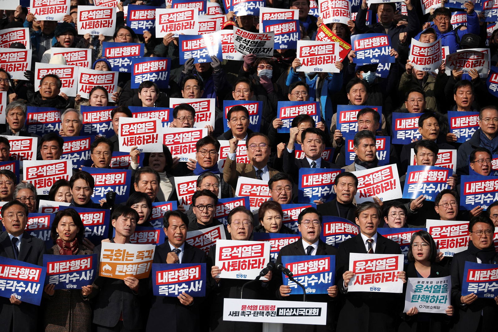 A crowd of peopel carrying signs in Korean