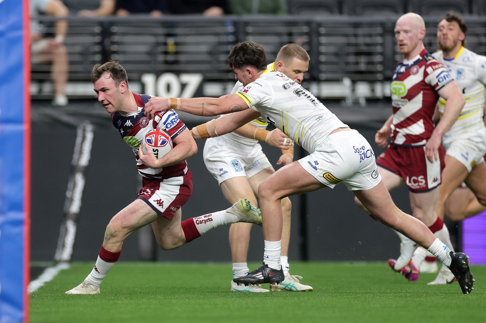 A Wigan Warriors player runs past the Warrington Wolves defence.