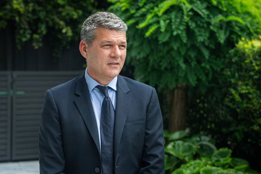 A man in a suit stands in his backyard