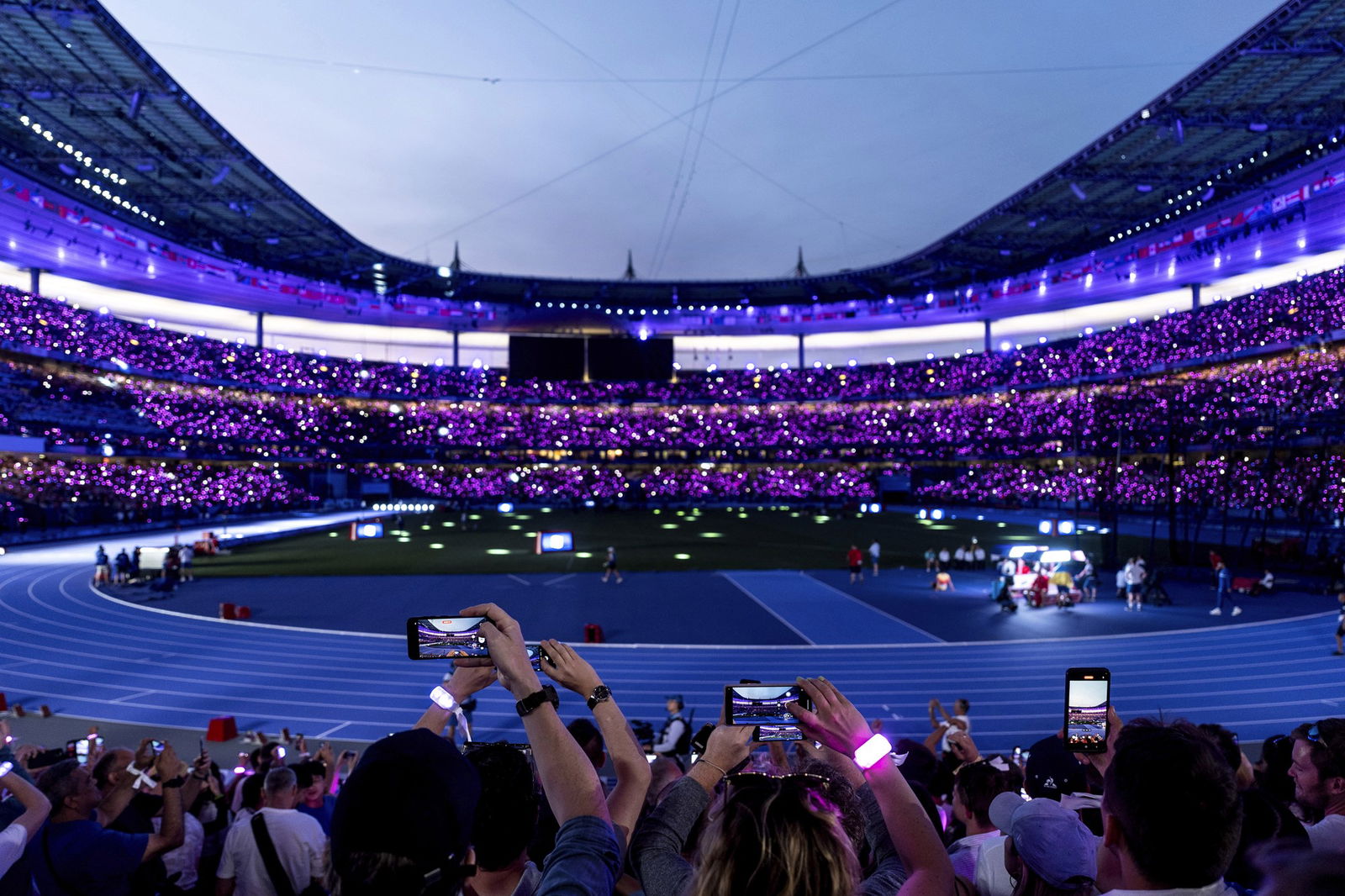 The crowd wear glowing wristbands as they wait for the start of the men's 100m final at the Stade de France.