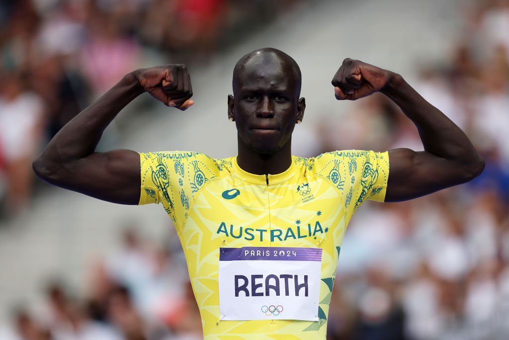 A black man in an Aussie outfit flexes.