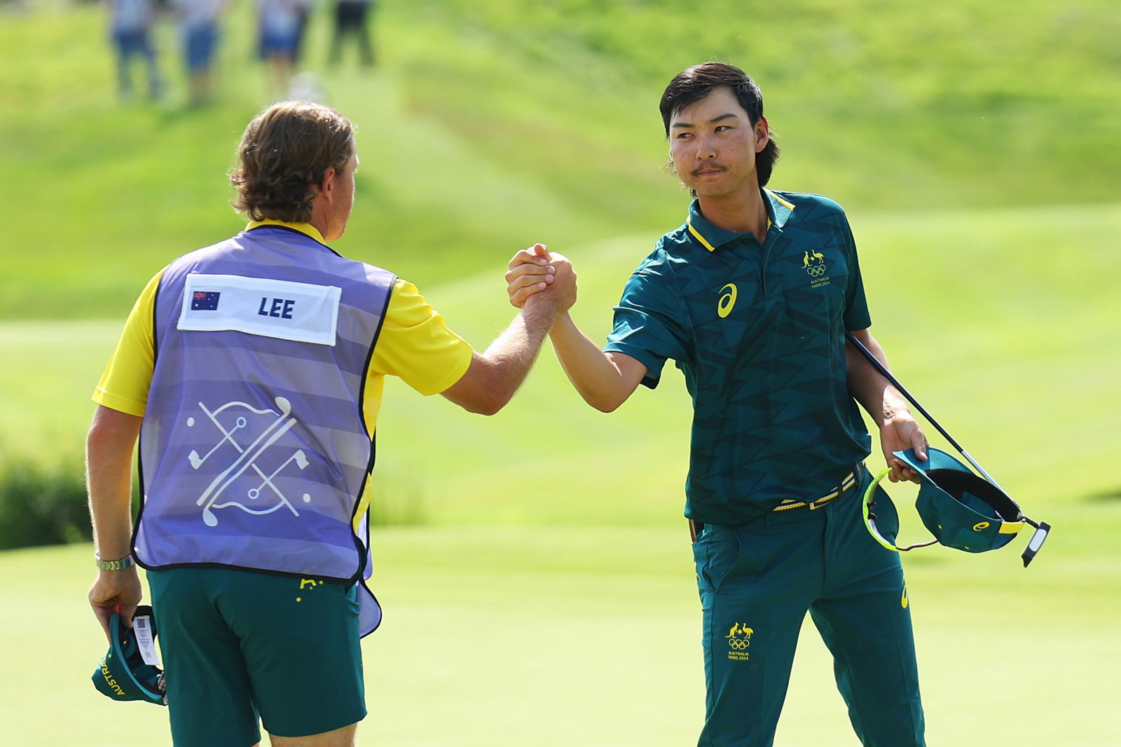 Min Woo Lee of Team Australia shakes hands with his caddie, Stuart Davidson on the 18th green during Day Two