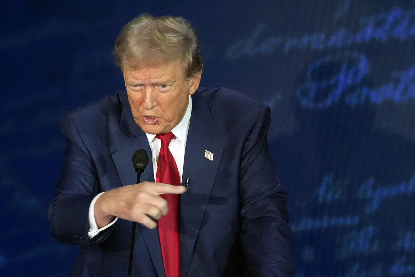 Donald Trump points to his left on a debate stage.