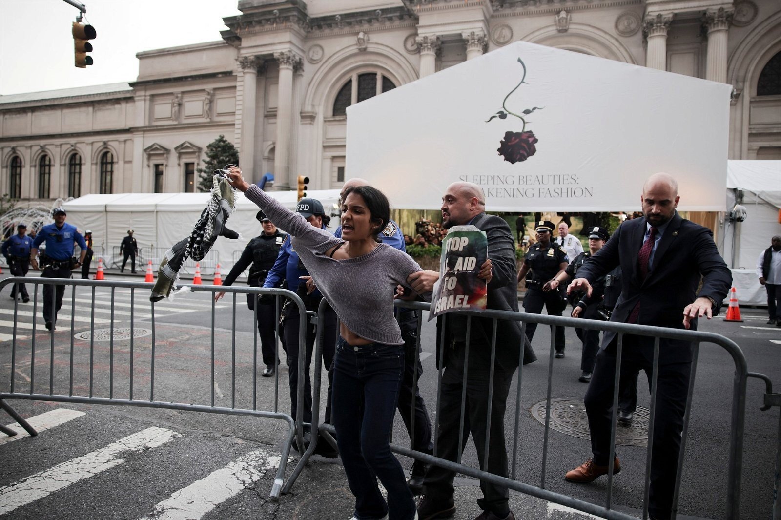 A woman yells as she's grabbed by a police officer outside the Met Gala.