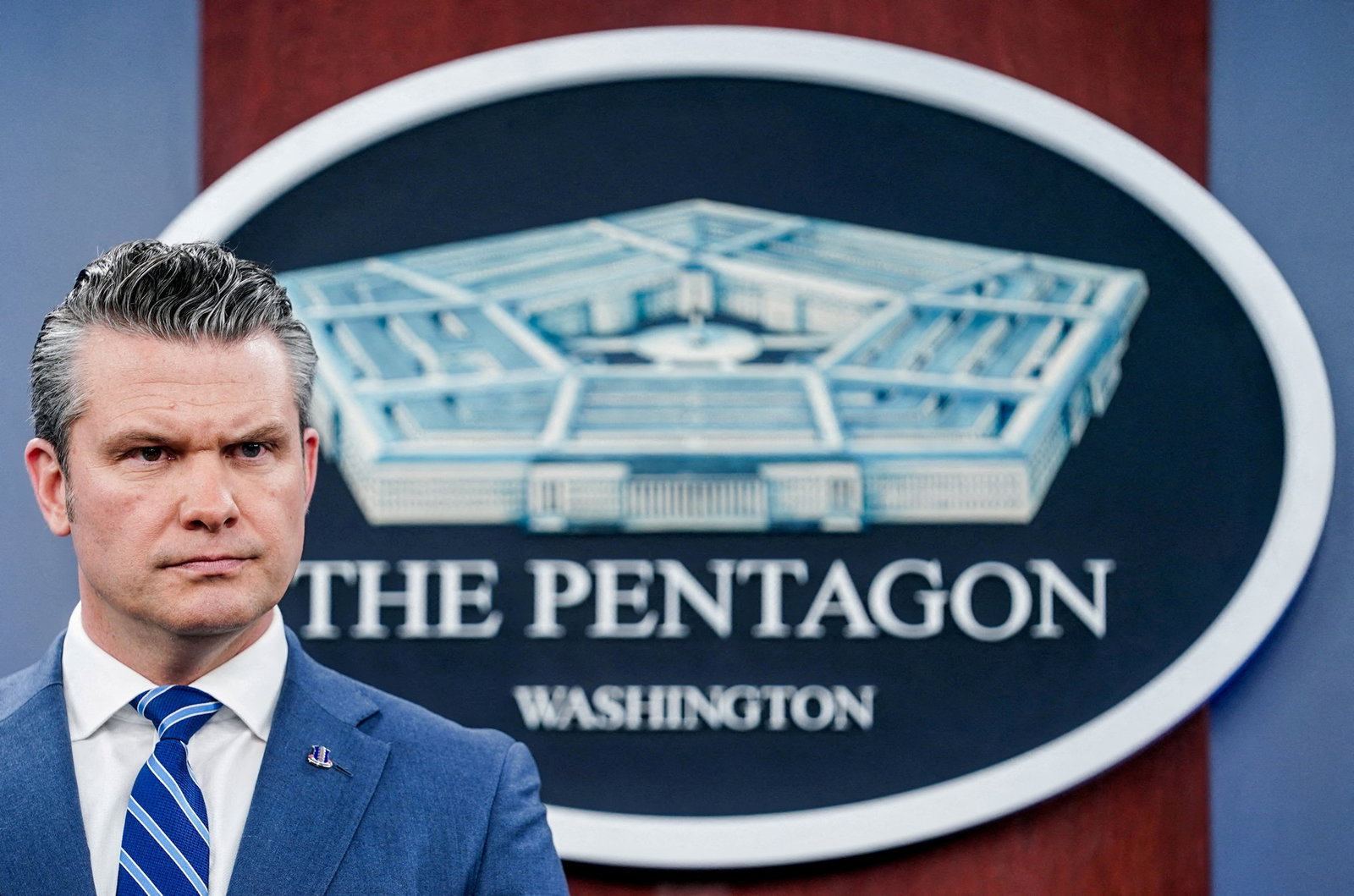 Hegseth furrows his brow as he stands in front of a Pentagon seal