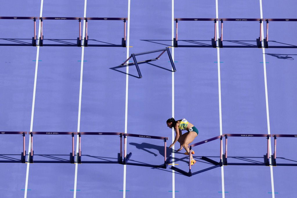 A woman hits a hurdle in the 100m