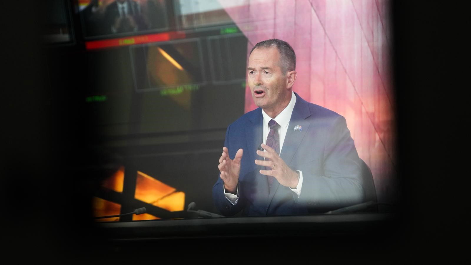 Una imagen de un monitor de televisión que muestra a un hombre de traje gesticulando mientras habla.