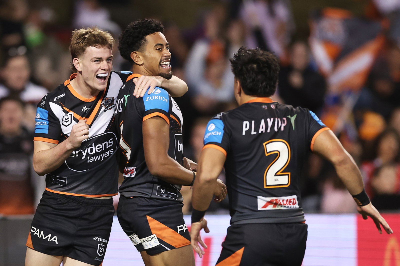 Wests Tigers players Lachlan Galvin, Jahream Bula and Solomona Faataape celebrate an NRL try.