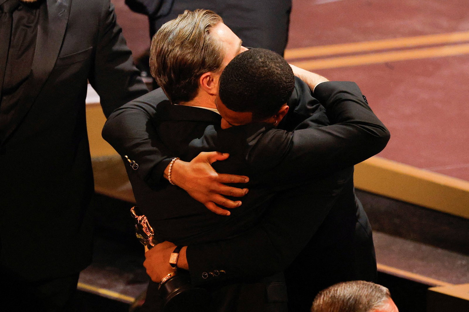 Two men hug after the Oscars show. One is holding an Oscar.