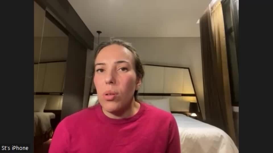 A woman in a hotel room in a red shirt 