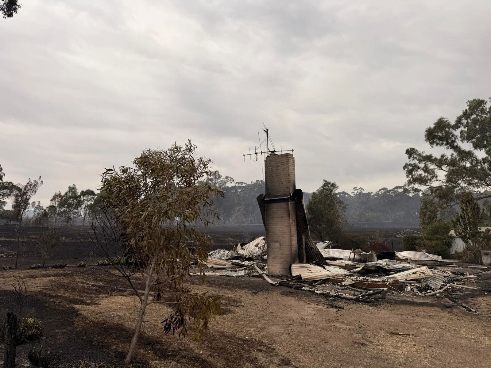 Um prédio queimado queima com fumaça ao fundo.