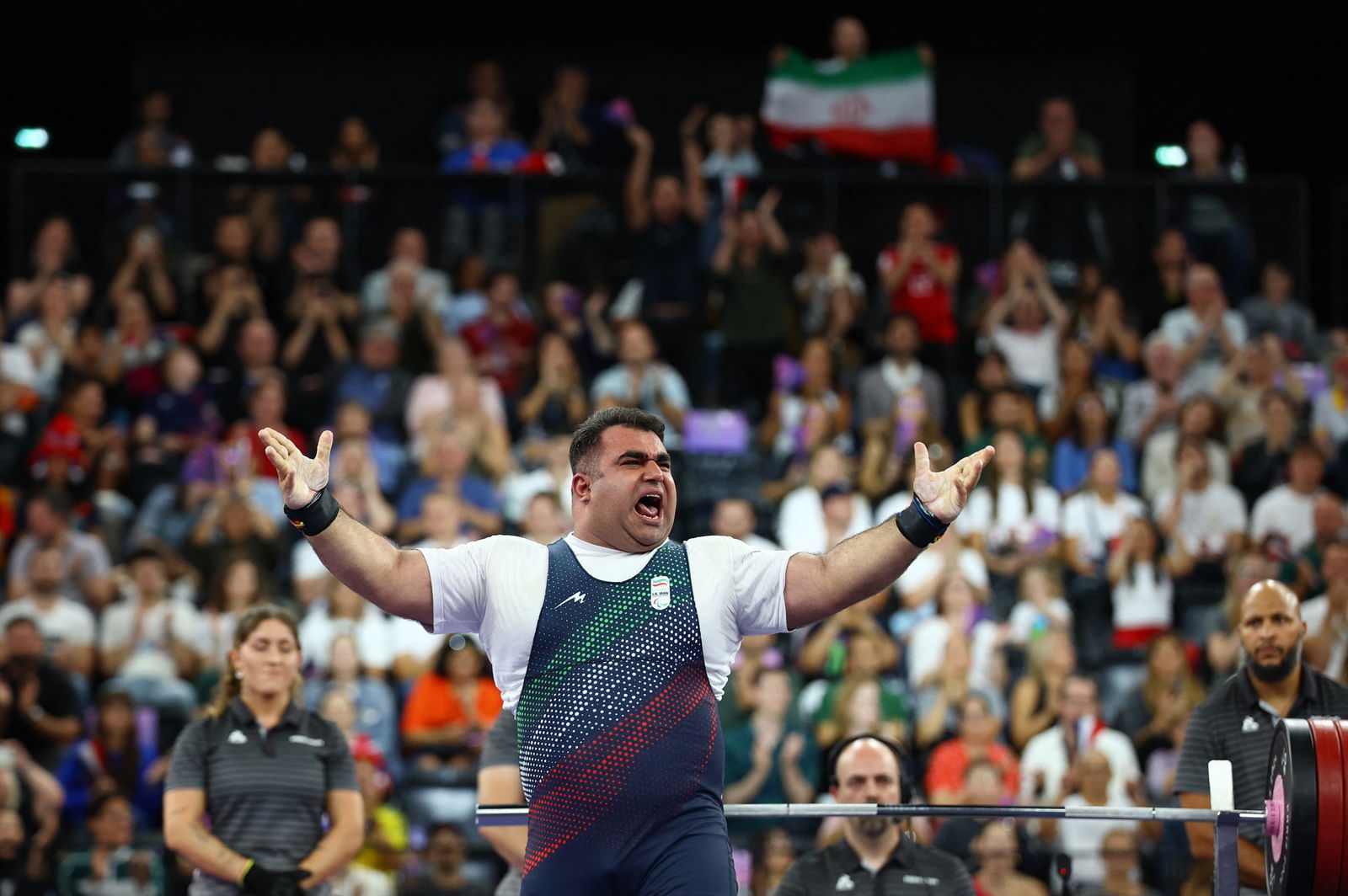 Ahmad Aminzadeh raises his arms and encourages a crowd to make noise