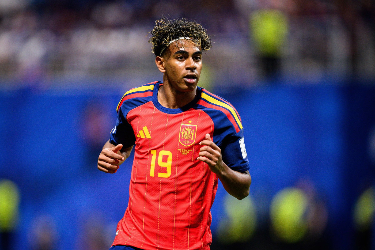 A shot of a soccer player in red with curly hair and headband