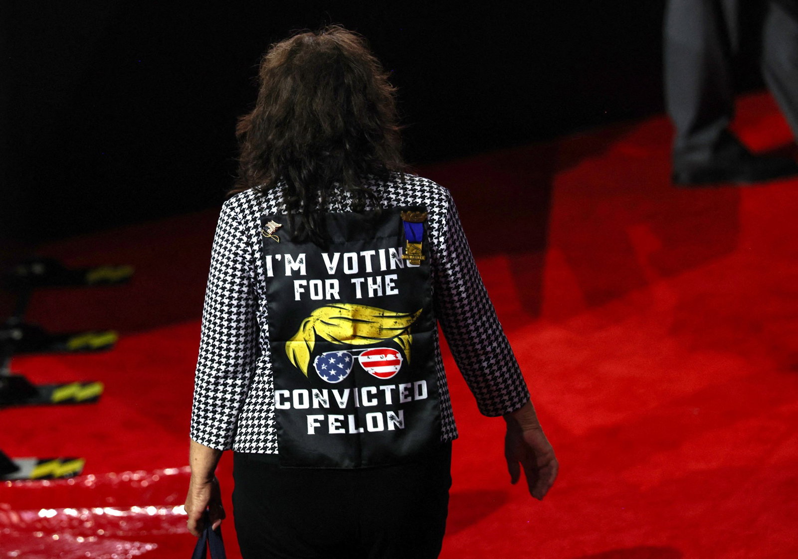 A woman wears a jacket that says I'm Voting for the Convicted Felon