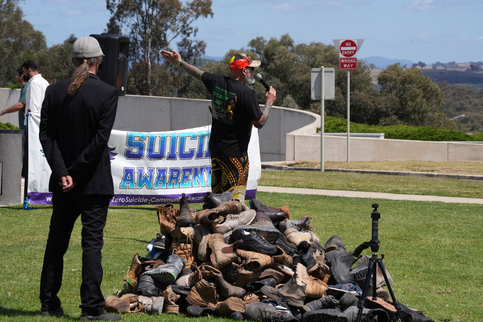 A pile of boots in front of a man with a microphone. 