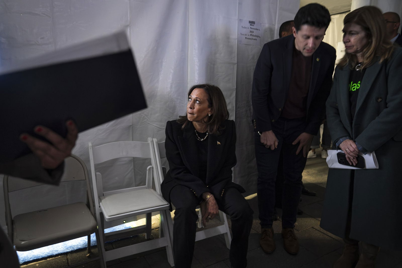 Kamala Harris sitting in a tent, looking up at a screen. 