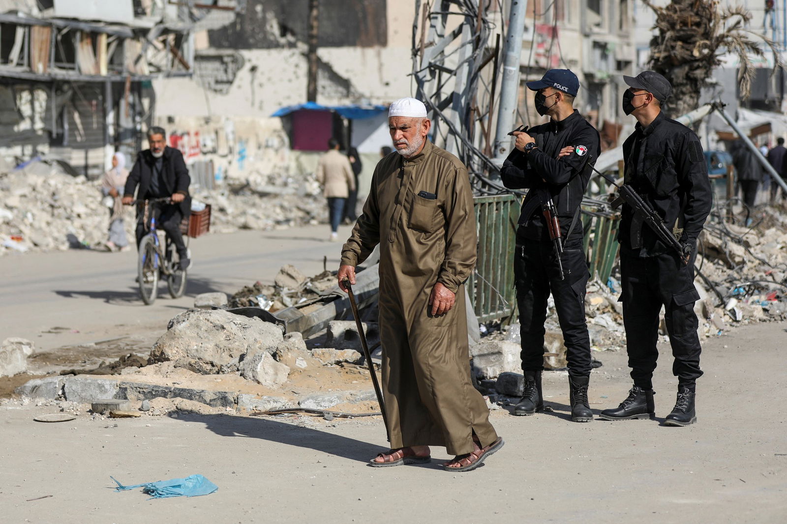 An older man walks past two police guards. 