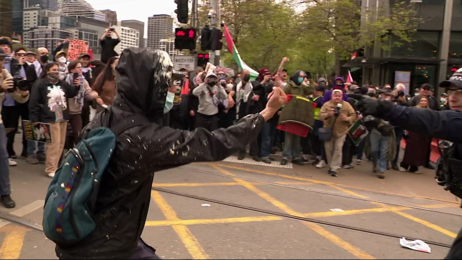 A protesters with their face covered in front of a crowd.