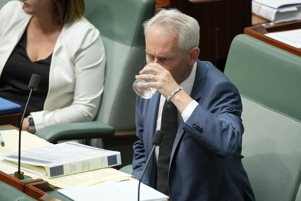 Andrew Giles drinks a glass of water as he sits in the House of Representatives.
