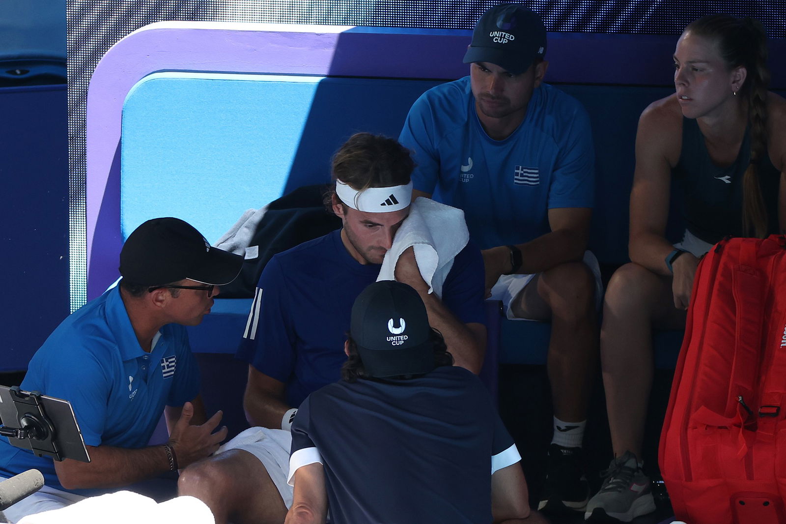 Stefanos Tsitsipas receives medical attention.