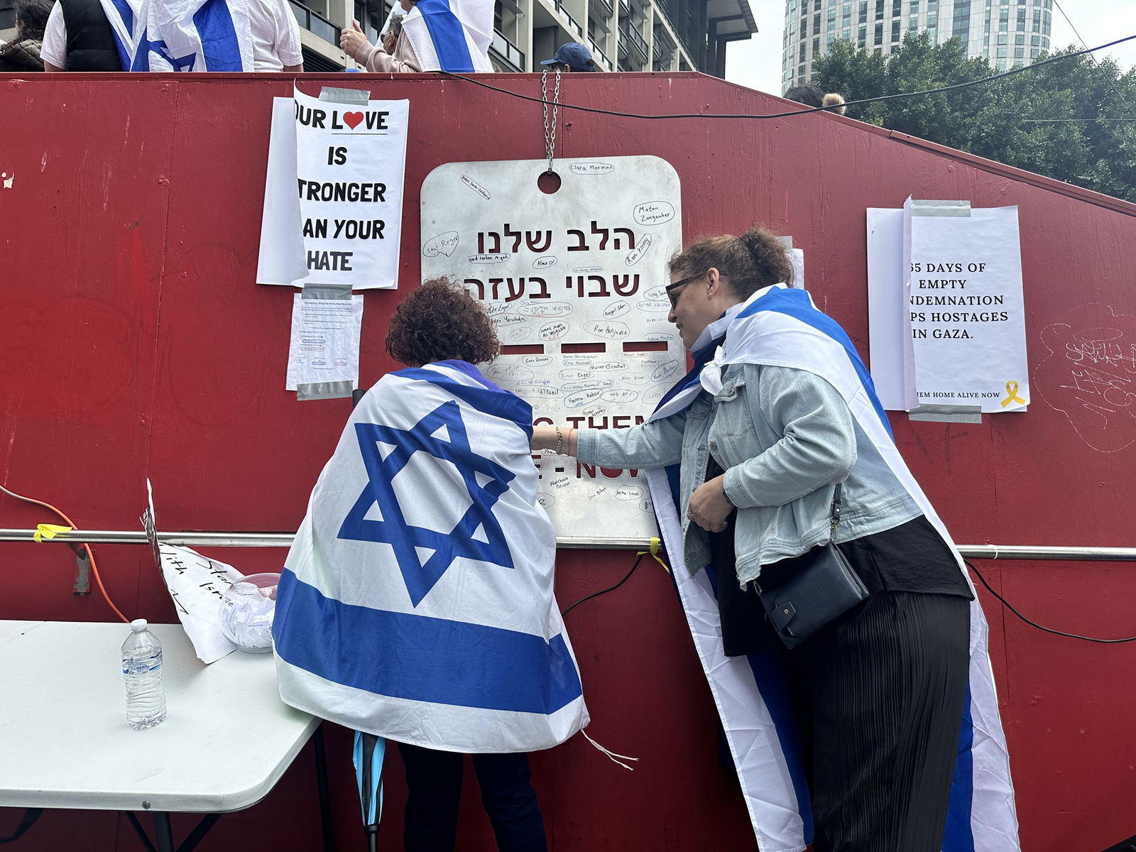 Two people draped in Israel flags putting up signs