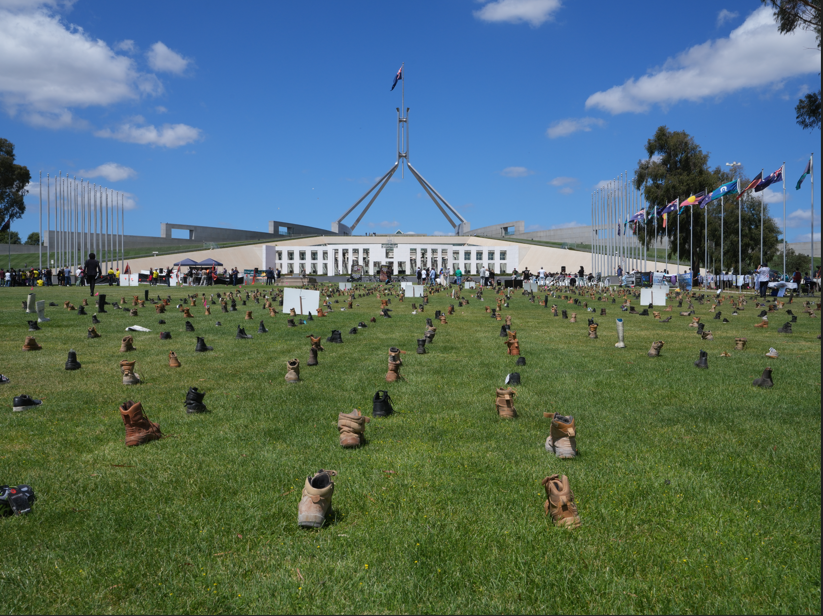 A photo of boots on the lawn in front of Parliament House. 