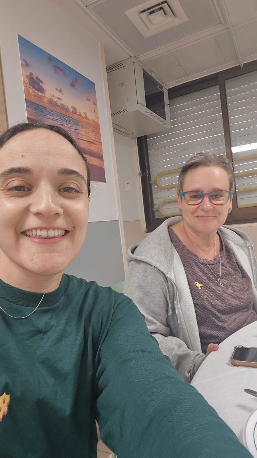 A girl in a green jumper taking a selfie with a woman in glasses. 