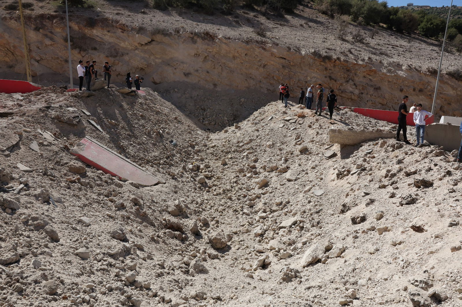 A huge divet in the dusty ground, with people standing on either side.