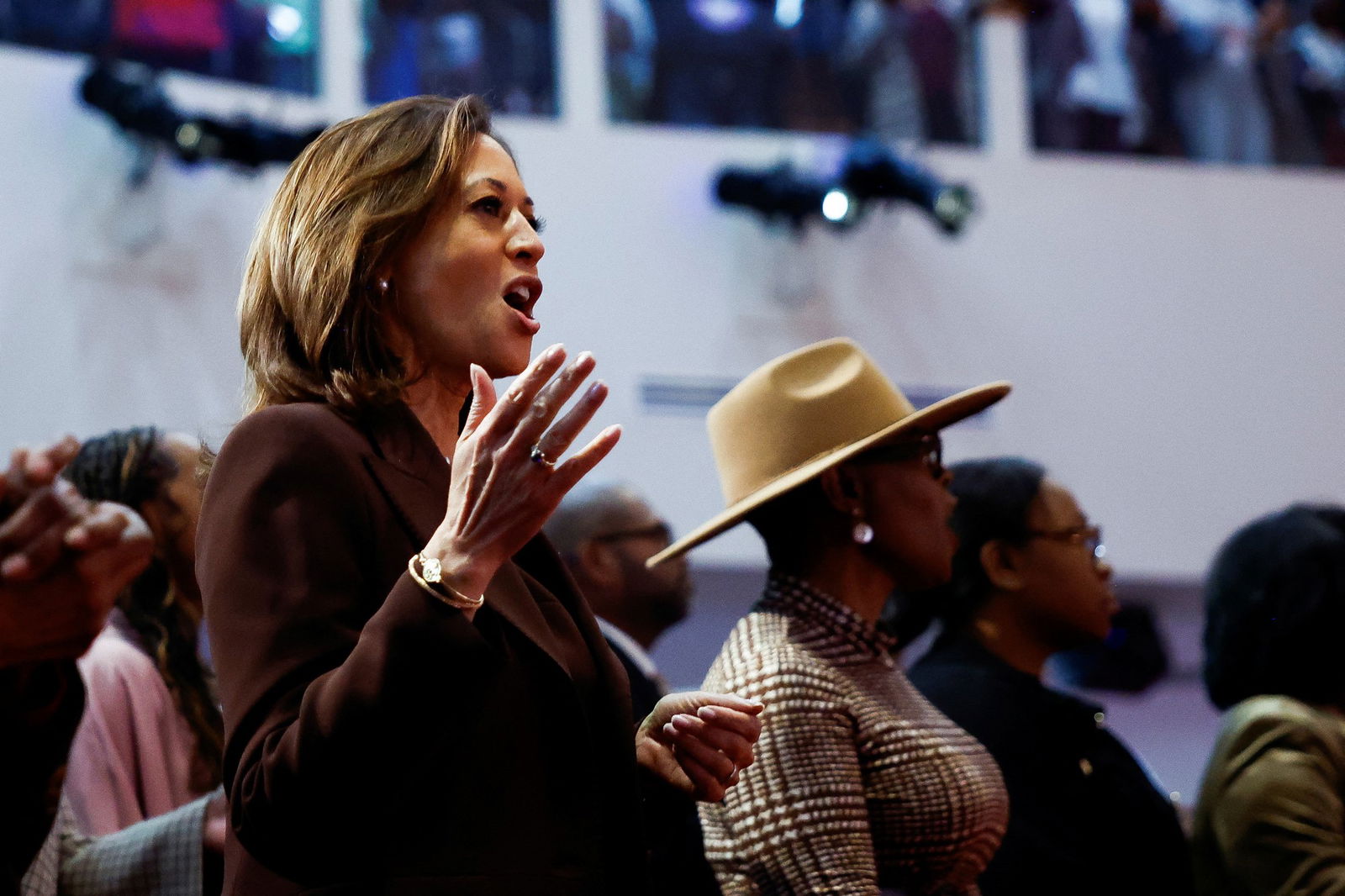 Kamala Harris raises a hand as she sings at a church