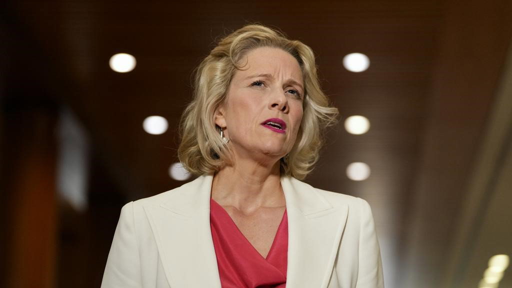 A women in a white blazer and red shirt responding to a question.