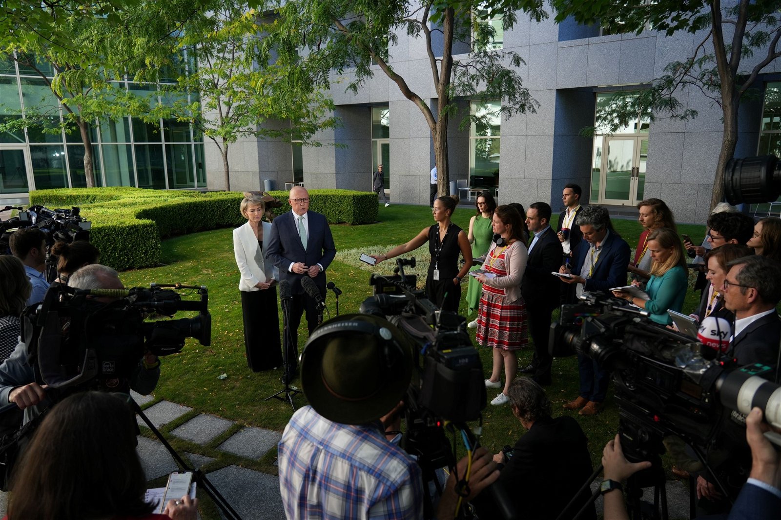 A crowd of press surround Peter Dutton in a courtyard. 