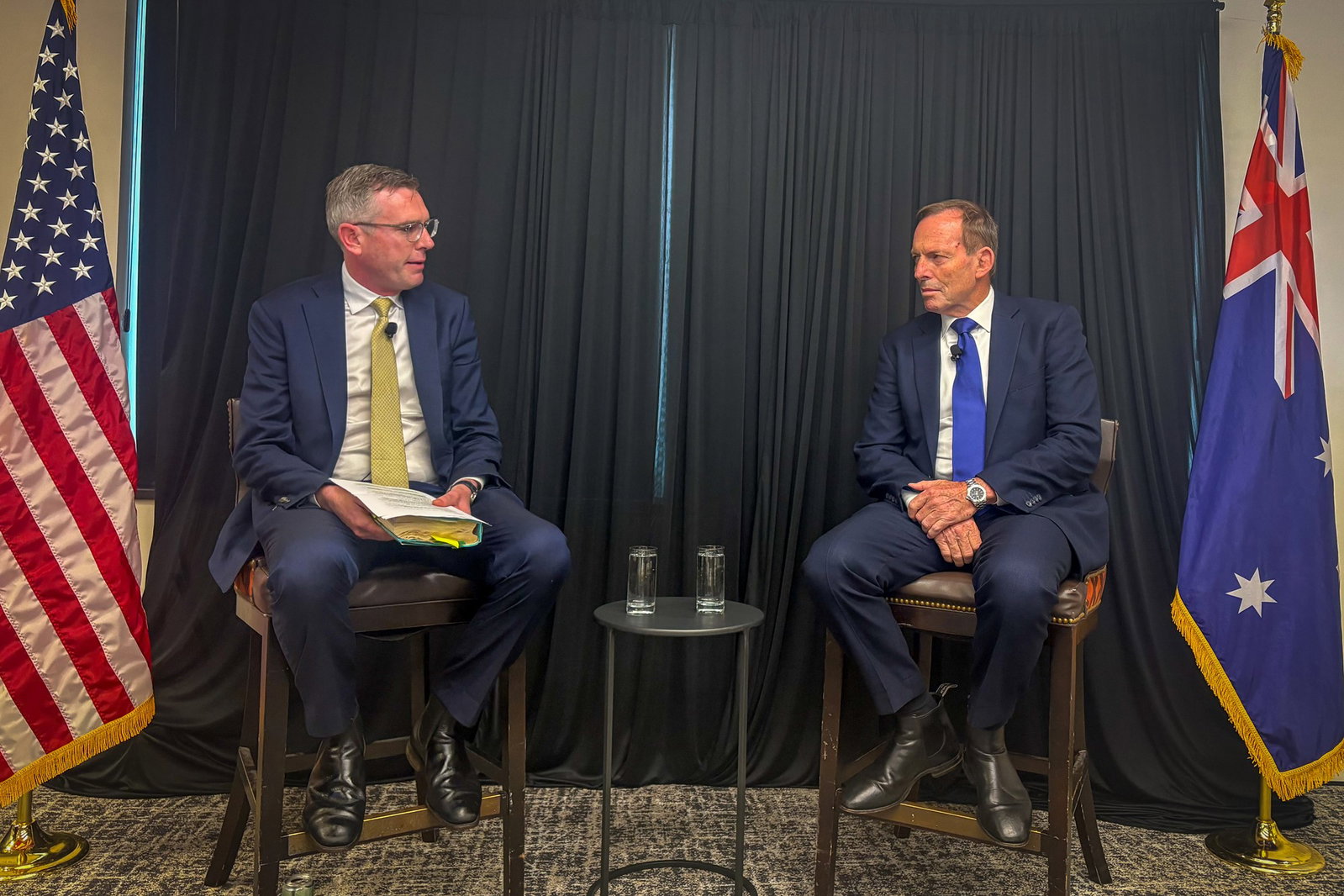 Dominic Perrottet and Tony Abbott sit between Australian and US flags.