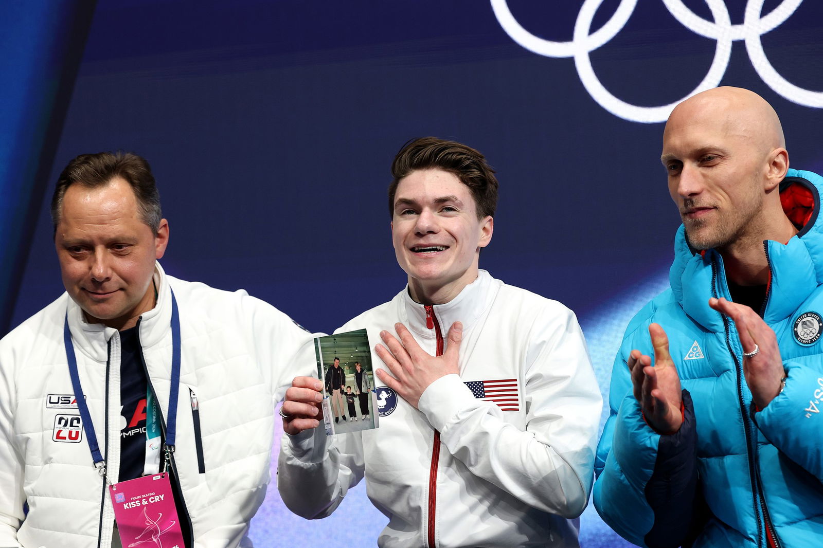 Maxim Naumov of Team United States reacts while holding a picture of his family in the Kiss and Cry zone after competing in Men's Single Skating - Short Program on day four of the Milano Cortina 2026 Winter Olympic games at Milano Ice Skating Arena on February 10, 2026 in Milan, Italy.