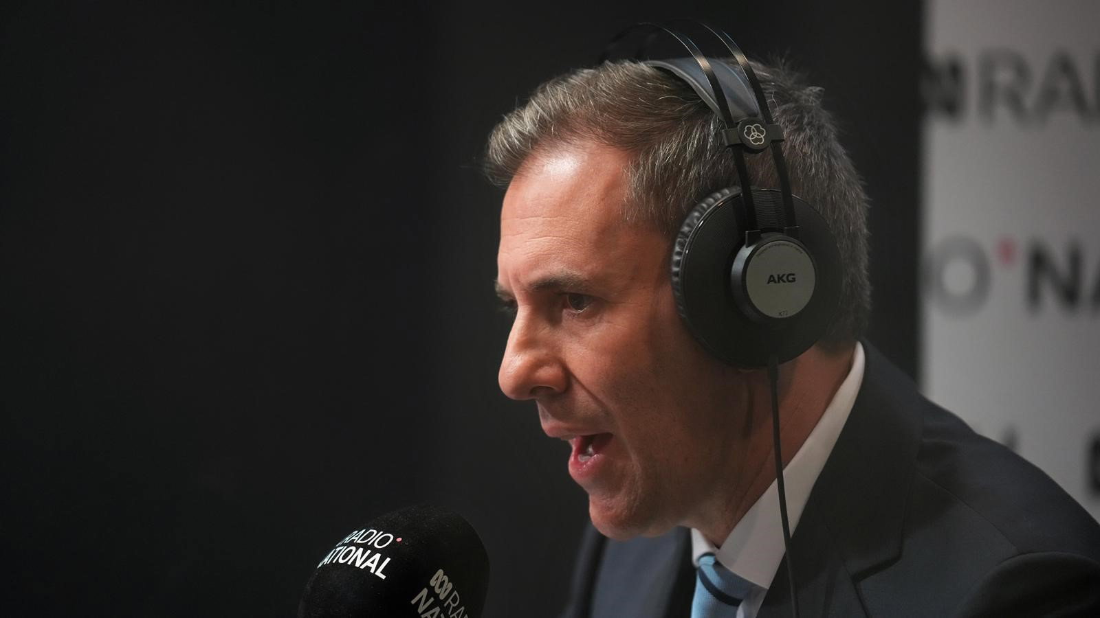 Chalmers speaks into a radio microphone and wears headphones.