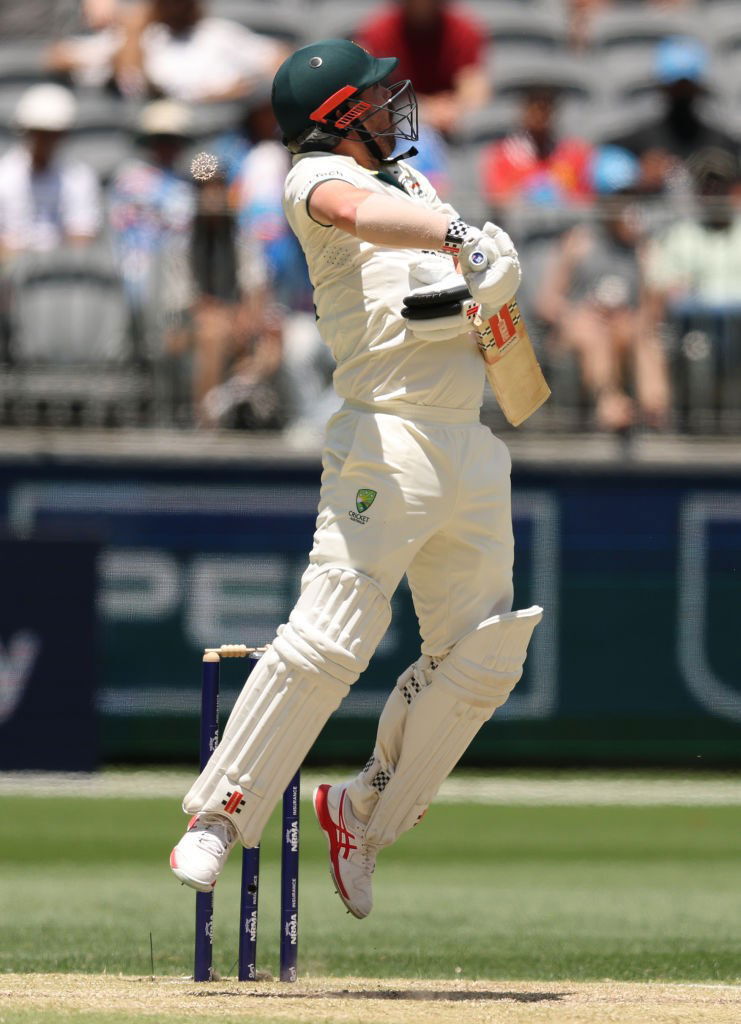 Travis Head jumps as a ball flies.