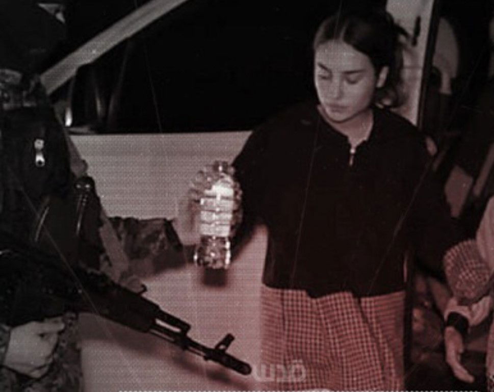 A man in uniform with a gun hands a woman a bottle of water.