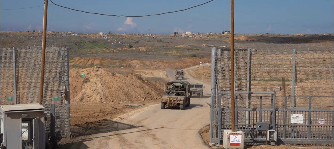 A large gate with several trucks driving through it.