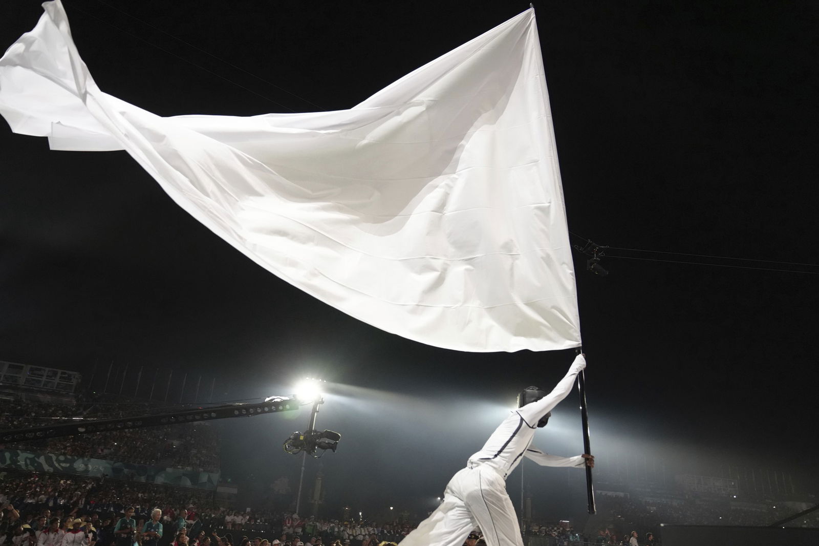 An artist carries a white flag during the Paralympics Opening Ceremony in Paris.