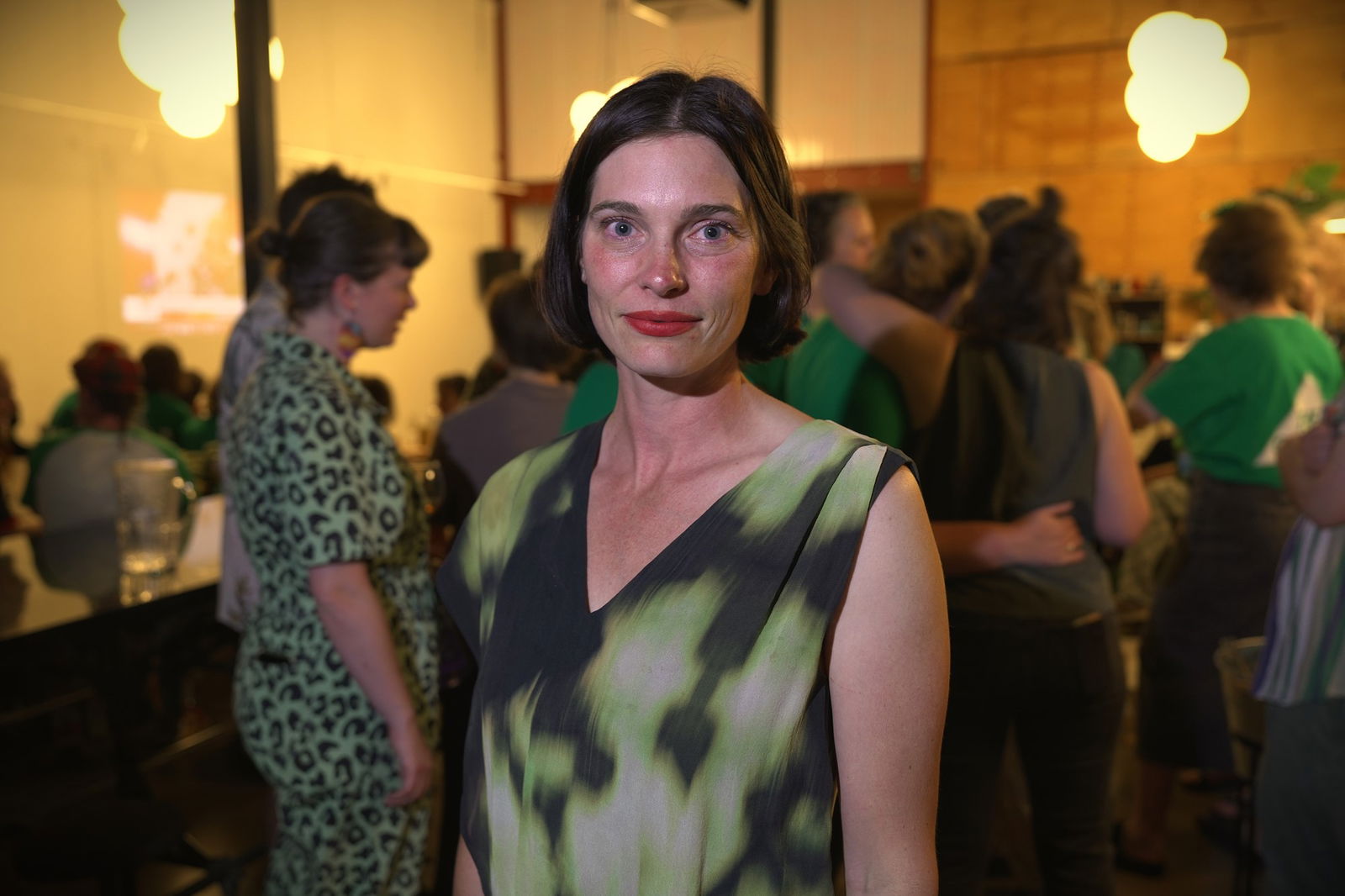 A woman in a green dress smiles at the camera.