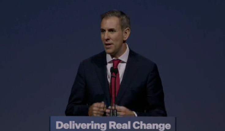 Treasurer Jim Chalmers speaks in front of a blue background.