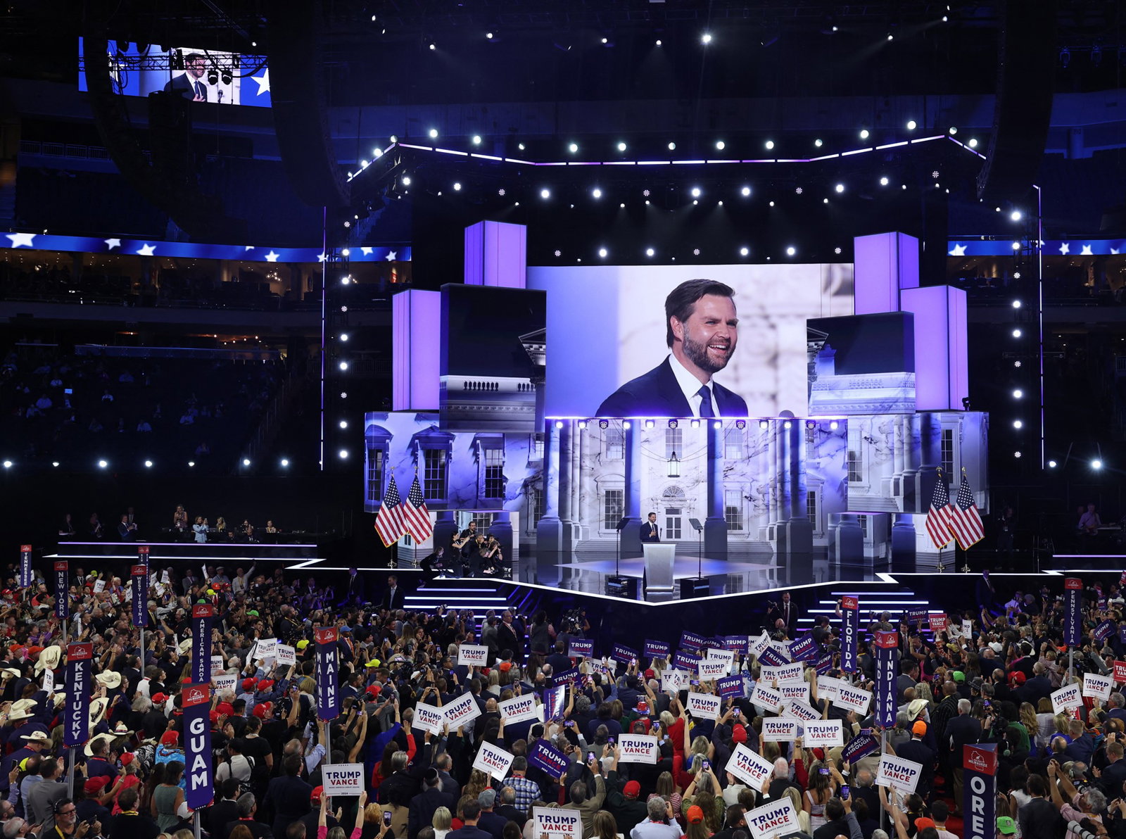 A wide shot of the Republican convention where JD Vance is shown smiling on the big screen