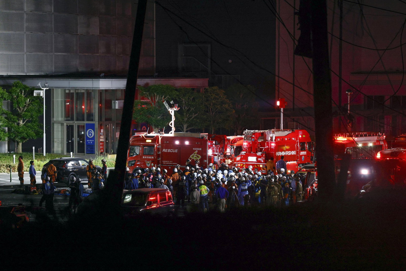 A crowd of emergency service personnel standing among fire trucks